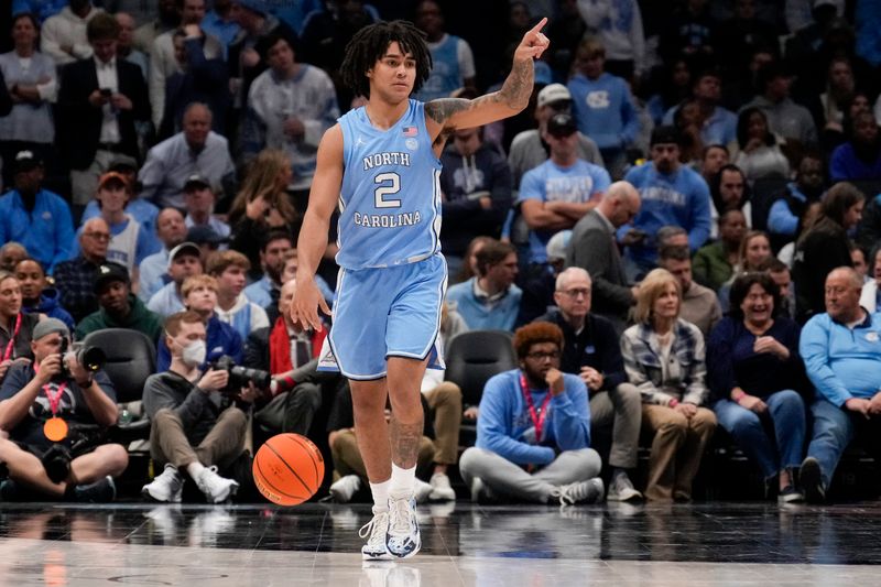 Dec 20, 2023; Charlotte, North Carolina, USA; North Carolina Tar Heels guard Elliot Cadeau (2) points to a teammate as he brings the ball up court during the second half at Spectrum Center. Mandatory Credit: Jim Dedmon-USA TODAY Sports