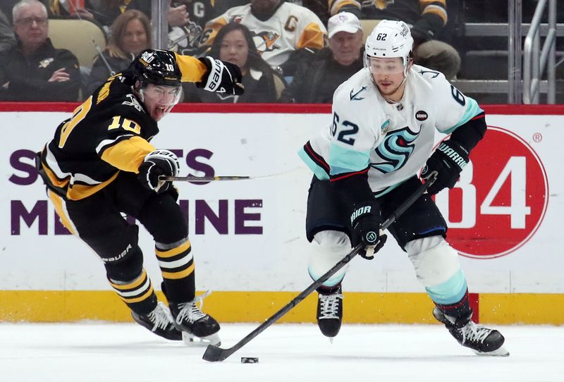 Jan 14, 2025; Pittsburgh, Pennsylvania, USA;  Seattle Kraken defenseman Brandon Montour (62) skates with the puck ahead of Pittsburgh Penguins left wing Drew O'Connor (10) during the third period at PPG Paints Arena. Mandatory Credit: Charles LeClaire-Imagn Images