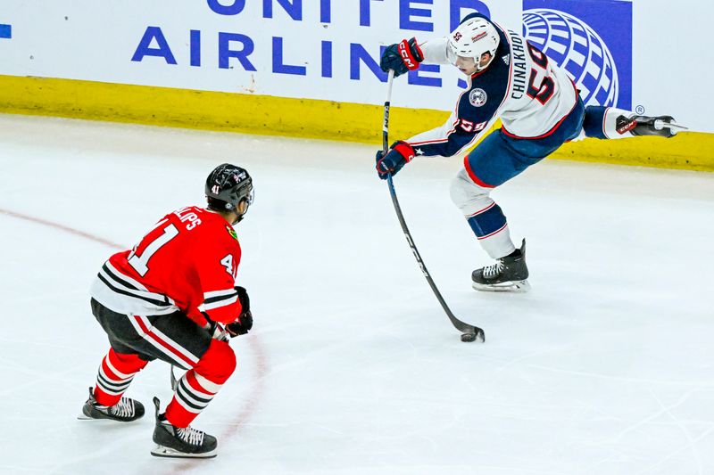 Mar 2, 2024; Chicago, Illinois, USA;  Columbus Blue Jackets right wing Yegor Chinakhov (59) shoots past Chicago Blackhawks defenseman Isaak Phillips (41) during the second period at the United Center. Mandatory Credit: Matt Marton-USA TODAY Sports