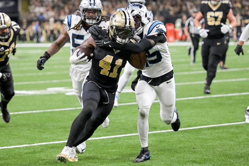 New Orleans Saints running back Alvin Kamara (41) runs the ball past Carolina Panthers safety Xavier Woods, right, during the second half of an NFL football game Sunday, Sept. 8, 2024, in New Orleans. (AP Photo/Matthew Hinton)