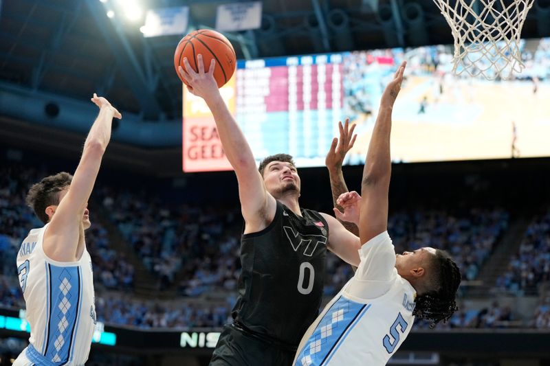 Feb 17, 2024; Chapel Hill, North Carolina, USA; Virginia Tech Hokies guard Hunter Cattoor (0) shoots as North Carolina Tar Heels guard Cormac Ryan (3) and forward Armando Bacot (5) defend in the first half at Dean E. Smith Center. Mandatory Credit: Bob Donnan-USA TODAY Sports