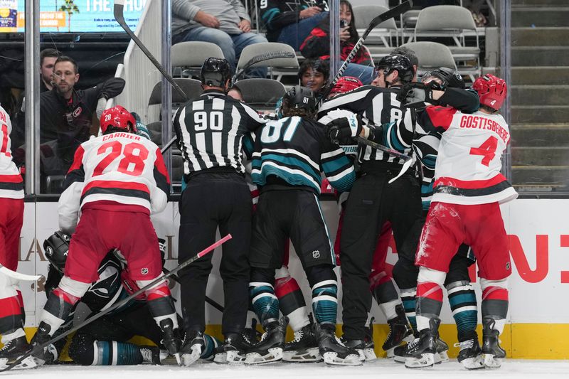 Oct 14, 2025; San Jose, California, USA;  Refs break up the fight between the San Jose Sharks and the Carolina Hurricanes during the third period at SAP Center at San Jose. Mandatory Credit: Stan Szeto-Imagn Images