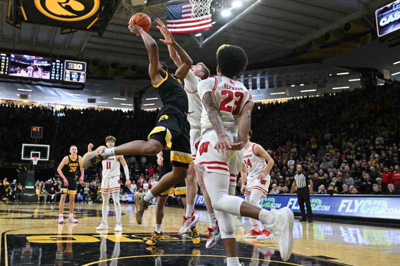 Feb 17, 2024; Iowa City, Iowa, USA; Iowa Hawkeyes guard Tony Perkins (11) scores the game winning basket during the overtime period as Wisconsin Badgers forward Steven Crowl (22) and guard Chucky Hepburn (23) defend at Carver-Hawkeye Arena. Mandatory Credit: Jeffrey Becker-USA TODAY Sports