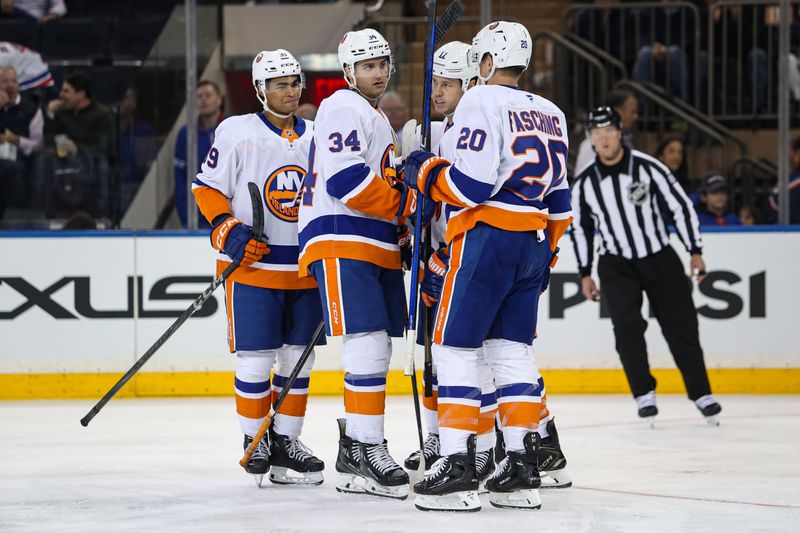 Sep 24, 2024; New York, New York, USA; New York Islanders left wing Matt Martin (17) celebrates his goal with defenseman Grant Hutton (34) and right wing Hudson Fasching (20) during the second period against the New York Rangers at Madison Square Garden. Mandatory Credit: Danny Wild-Imagn Images