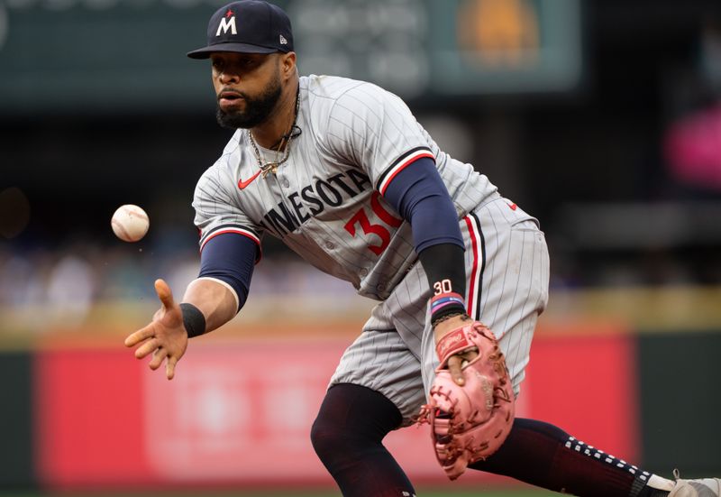 Jun 28, 2024; Seattle, Washington, USA; Minnesota Twins first baseman Carlos Santana (30) tosses the ball to first base for an out during the third inning against the Seattle Mariners at T-Mobile Park. Mandatory Credit: Stephen Brashear-USA TODAY Sports