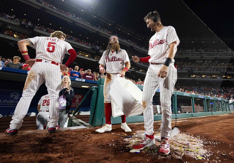 Aug 22, 2023; Philadelphia, Pennsylvania, USA; Philadelphia Phillies second baseman Bryson Stott (5)  and center fielder Brandon Marsh (M) douse shortstop Trea Turner (R) with water after his game winning two RBI single against the San Francisco Giants during the ninth inning at Citizens Bank Park. Mandatory Credit: Bill Streicher-USA TODAY Sports