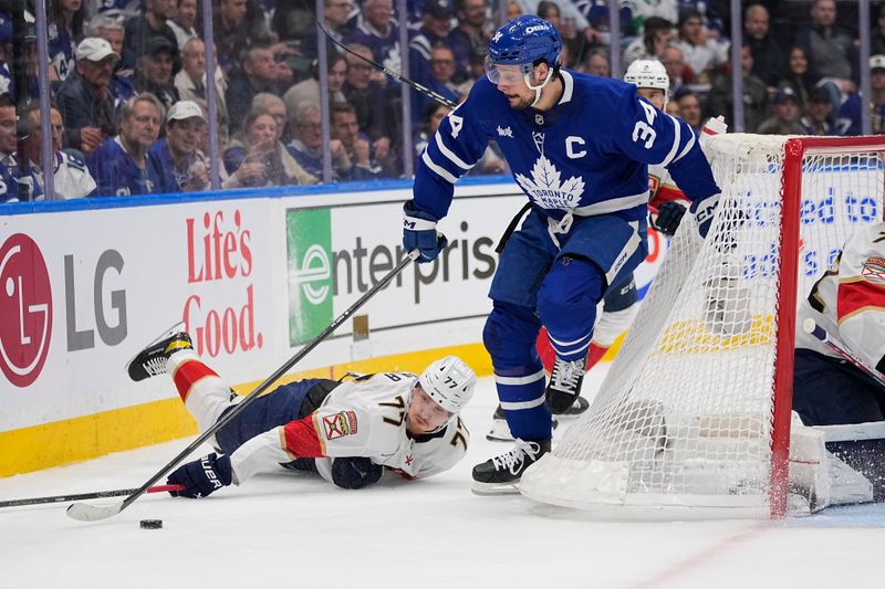 May 14, 2025; Toronto, Ontario, CAN; Toronto Maple Leafs forward Auston Matthews (34) gains control of the puck against Florida Panthers defenseman Niko Mikkola (77) during the first period of game five of the second round of the 2025 Stanley Cup Playoffs at Scotiabank Arena. Mandatory Credit: John E. Sokolowski-Imagn Images