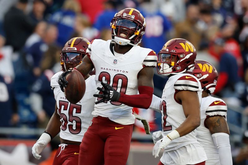 Washington Commanders safety Jartavius Martin (20) celebrates with defensive end KJ Henry (55) and safety Terrell Burgess, second from right, after intercepting a pass intended for New England Patriots wide receiver JuJu Smith-Schuster (not shown) in the second half of an NFL football game, Sunday, Nov. 5, 2023, in Foxborough, Mass. (AP Photo/Michael Dwyer)