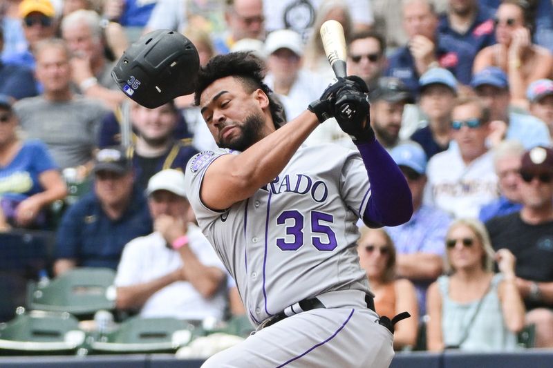 Aug 9, 2023; Milwaukee, Wisconsin, USA; Colorado Rockies catcher Elias Diaz (35) loses his helmet while swinging at a pitch against the Milwaukee Brewers in the ninth inning at American Family Field. Mandatory Credit: Benny Sieu-USA TODAY Sports