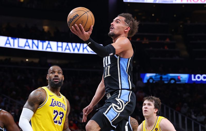 ATLANTA, GEORGIA - JANUARY 30:  Trae Young #11 of the Atlanta Hawks drives against LeBron James #23 and Austin Reaves #15 of the Los Angeles Lakers during the third quarter at State Farm Arena on January 30, 2024 in Atlanta, Georgia.  NOTE TO USER: User expressly acknowledges and agrees that, by downloading and/or using this photograph, user is consenting to the terms and conditions of the Getty Images License Agreement.  (Photo by Kevin C. Cox/Getty Images). (Photo by Kevin C. Cox/Getty Images)