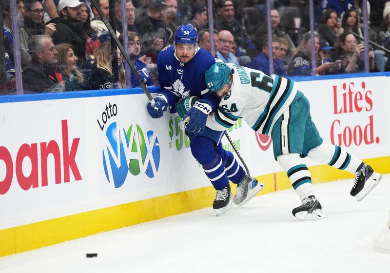 Jan 9, 2024; Toronto, Ontario, CAN; Toronto Maple Leafs center Auston Matthews (34) battles for the puck along the boards with San Jose Sharks center Mikael Granlund (64) during the third period at Scotiabank Arena. Mandatory Credit: Nick Turchiaro-USA TODAY Sports