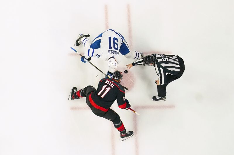 Mar 24, 2024; Raleigh, North Carolina, USA;  Carolina Hurricanes center Jordan Staal (11) and Toronto Maple Leafs center John Tavares (91) take a face off during the second period at PNC Arena. Mandatory Credit: James Guillory-USA TODAY Sports