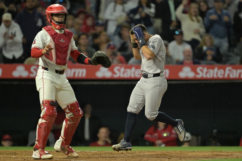 May 30, 2024; Anaheim, California, USA;  New York Yankees shortstop Anthony Volpe (11) ducks as he scores on a triple by right fielder Juan Soto (22) in the seventh inning against the Los Angeles Angels at Angel Stadium. Mandatory Credit: Jayne Kamin-Oncea-USA TODAY Sports