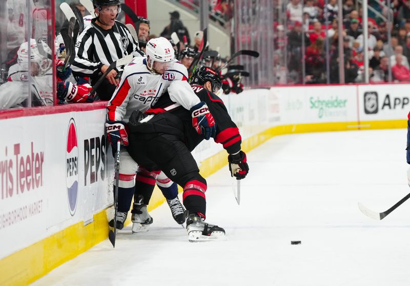 Nov 3, 2024; Raleigh, North Carolina, USA;  Carolina Hurricanes defenseman Dmitry Orlov (7) checks Washington Capitals center Connor McMichael (24) during the second period at Lenovo Center. Mandatory Credit: James Guillory-Imagn Images