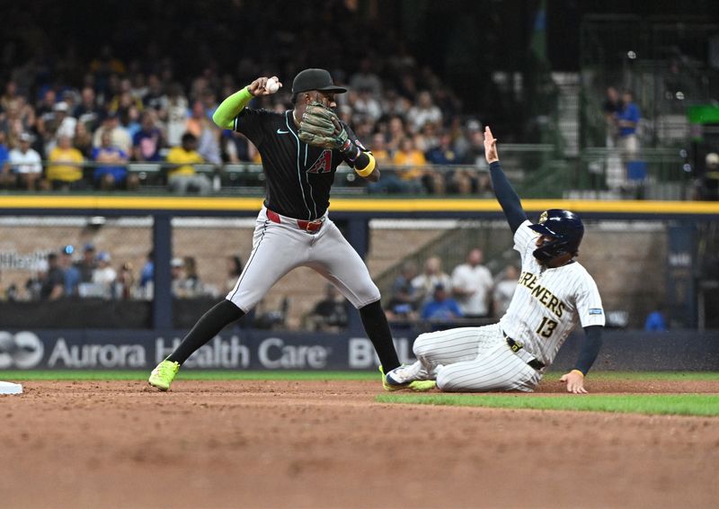 Sep 21, 2024; Milwaukee, Wisconsin, USA; Milwaukee Brewers catcher Eric Haase (13) attempts to break up the double play by Arizona Diamondbacks shortstop Geraldo Perdomo (2) in the third inning at American Family Field. Mandatory Credit: Michael McLoone-Imagn Images