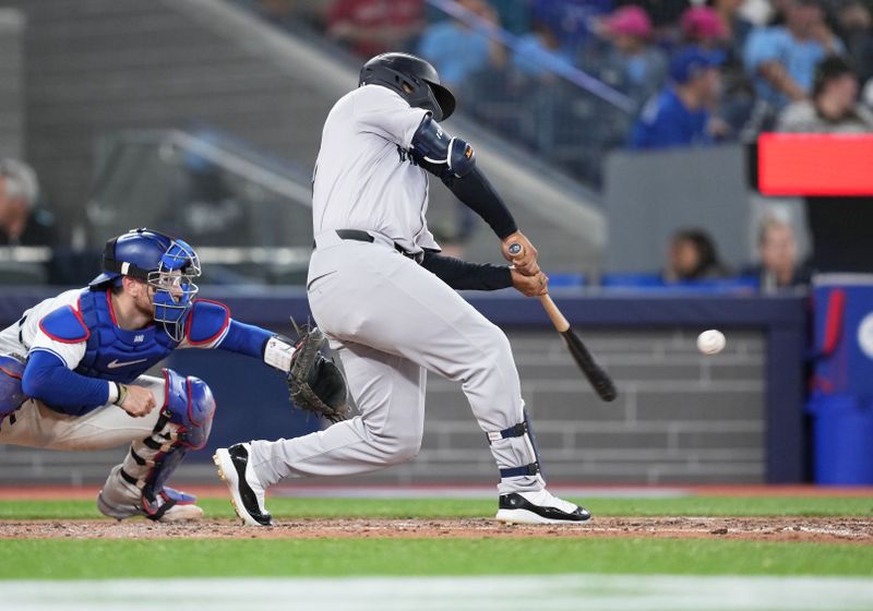 Jun 30, 2024; Toronto, Ontario, CAN; New York Yankees center fielder Trent Grisham (12) hits a two RBI double against the Toronto Blue Jays during the fifth inning at Rogers Centre. Mandatory Credit: Nick Turchiaro-USA TODAY Sports