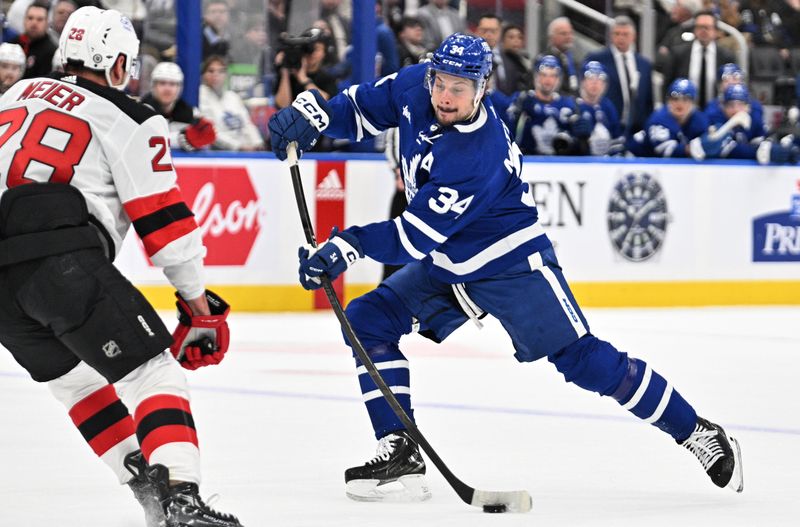 Apr 11, 2024; Toronto, Ontario, CAN; Toronto Maple Leafs forward Auston Matthews (34) shoots the puck past New Jersey Devils forward Timo Meier (28) in the first period at Scotiabank Arena. Mandatory Credit: Dan Hamilton-USA TODAY Sports