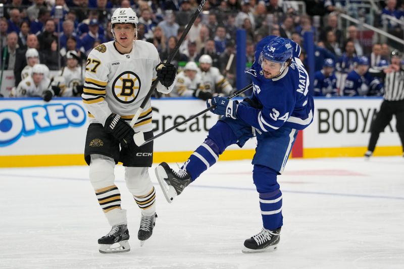 Apr 24, 2024; Toronto, Ontario, CAN; Toronto Maple Leafs forward Auston Matthews (34) tries to maintain his balance after a collision with Boston Bruins defenseman Hampus Lindholm (27) during the first period of game three of the first round of the 2024 Stanley Cup Playoffs at Scotiabank Arena. Mandatory Credit: John E. Sokolowski-USA TODAY Sports