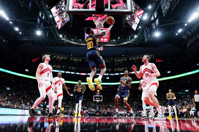 TORONTO, ON - NOVEMBER 18: Bennedict Mathurin #00 of the Indiana Pacers goes to the basket against Jakob Poeltl #19 and Gradey Dick #1 of the Toronto Raptors during the second half at Scotiabank Arena on November 18, 2024 in Toronto, Ontario, Canada. NOTE TO USER: User expressly acknowledges and agrees that, by downloading and/or using this Photograph, user is consenting to the terms and conditions of the Getty Images License Agreement. (Photo by Mark Blinch/Getty Images)