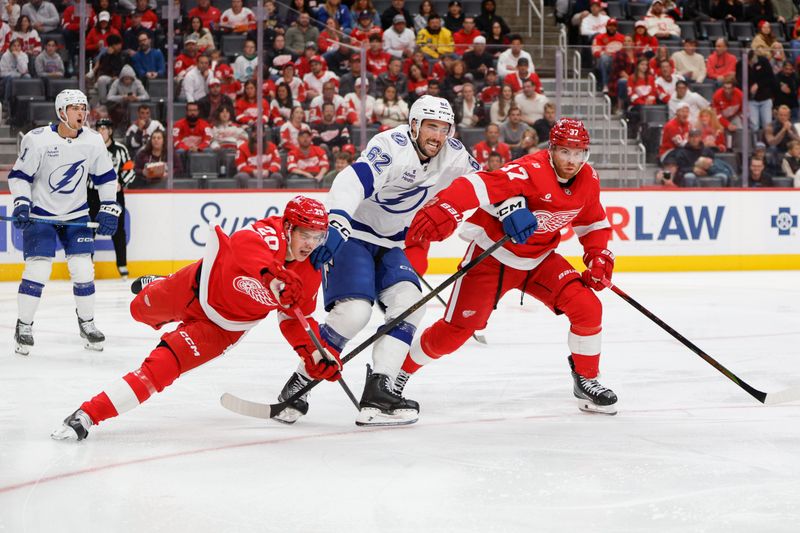 Oct 17, 2025; Detroit, Michigan, USA; Detroit Red Wings defenseman Albert Johansson (20) left wing J.T. Compher (37) and Tampa Bay Lightning center Jack Finley (62) fight for control of the puck during the third period at Little Caesars Arena. Mandatory Credit: Brian Bradshaw Sevald-Imagn Images