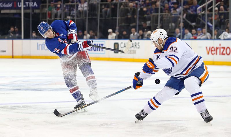 Mar 16, 2025; New York, New York, USA; New York Rangers defenseman Adam Fox (23) fires a puck into Edmonton Oilers right wing Vasily Podkolzin (92) during the second period at Madison Square Garden. Mandatory Credit: Danny Wild-Imagn Images