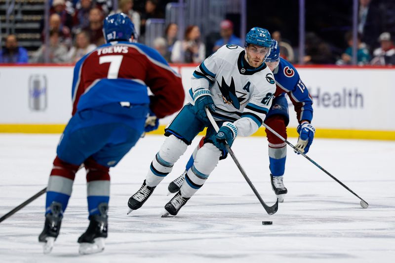 Feb 4, 2026; Denver, Colorado, USA; San Jose Sharks center Alexander Wennberg (21) controls the puck as Colorado Avalanche defenseman Devon Toews (7) defends in the first period at Ball Arena. Mandatory Credit: Isaiah J. Downing-Imagn Images