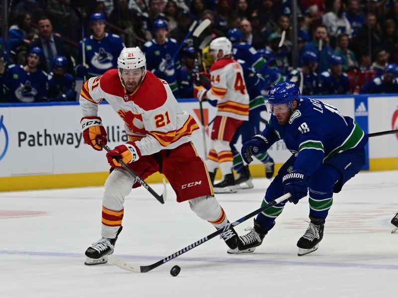 sMar 23, 2024; Vancouver, British Columbia, CAN; Calgary Flames forward Kevin Rooney (21) skates with puck against Vancouver Canucks forward J.T. Lafferty (19) during the second period at Rogers Arena. Mandatory Credit: Simon Fearn-USA TODAY Sports