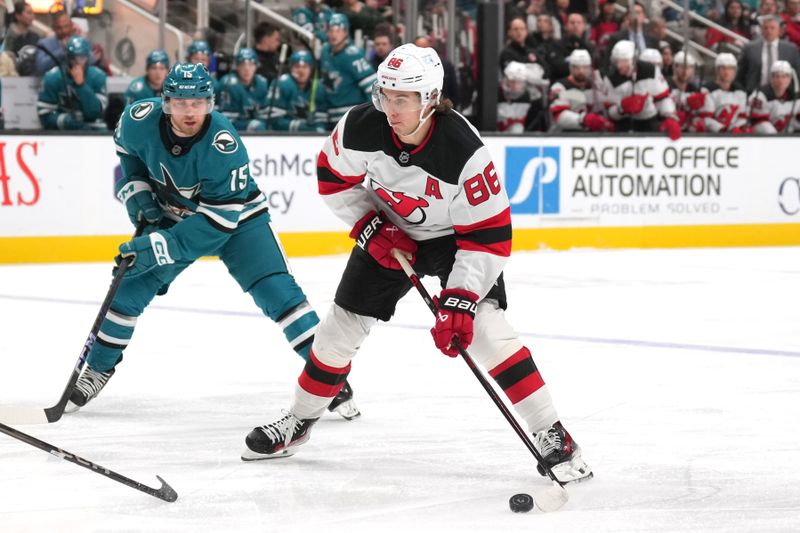 Jan 4, 2025; San Jose, California, USA; New Jersey Devils center Jack Hughes (86) skates with the puck against San Jose Sharks right wing Nikolai Kovalenko (15) during the first period at SAP Center at San Jose. Mandatory Credit: Darren Yamashita-Imagn Images