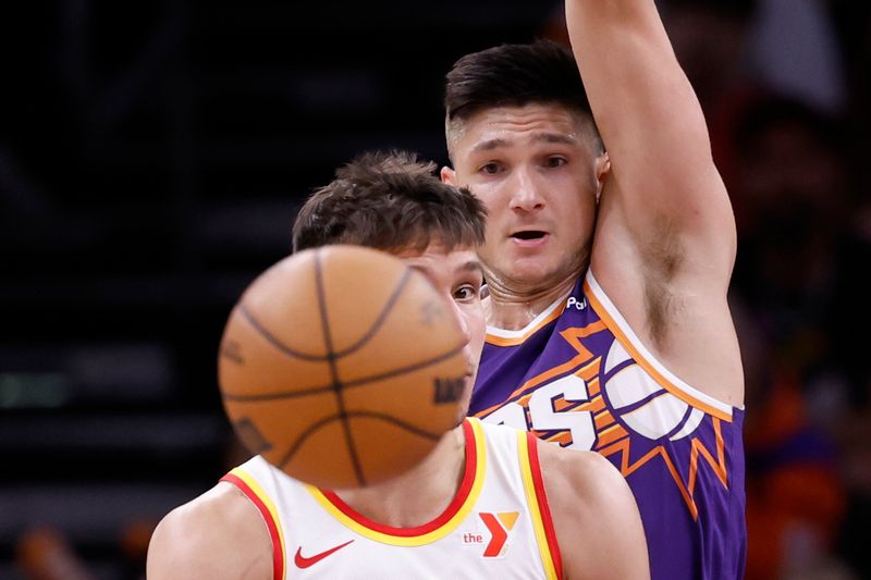 PHOENIX, ARIZONA - MARCH 21: Bogdan Bogdanovic #13 of the Atlanta Hawks watches his pass under pressure from Grayson Allen #8 of the Phoenix Suns during the second half at Footprint Center on March 21, 2024 in Phoenix, Arizona. NOTE TO USER: User expressly acknowledges and agrees that, by downloading and or using this photograph, User is consenting to the terms and conditions of the Getty Images License Agreement.  (Photo by Chris Coduto/Getty Images)