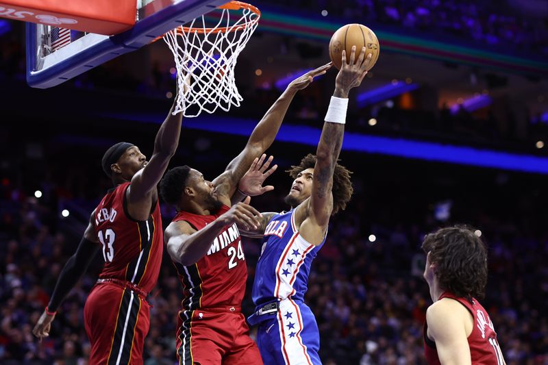 PHILADELPHIA, PENNSYLVANIA - MARCH 18: Kelly Oubre Jr. #9 of the Philadelphia 76ers shoots a lay up past Bam Adebayo #13 and Haywood Highsmith #24 of the Miami Heat during the second quarter at the Wells Fargo Center on March 18, 2024 in Philadelphia, Pennsylvania. NOTE TO USER: User expressly acknowledges and agrees that, by downloading and or using this photograph, User is consenting to the terms and conditions of the Getty Images License Agreement.  (Photo by Tim Nwachukwu/Getty Images)