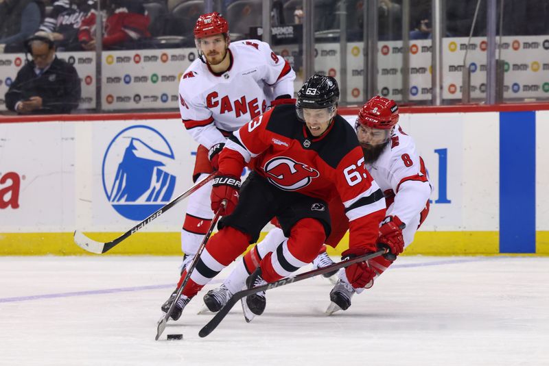 Nov 21, 2024; Newark, New Jersey, USA; New Jersey Devils left wing Jesper Bratt (63) skates with the puck while being defended by Carolina Hurricanes defenseman Brent Burns (8) during the second period at Prudential Center. Mandatory Credit: Ed Mulholland-Imagn Images