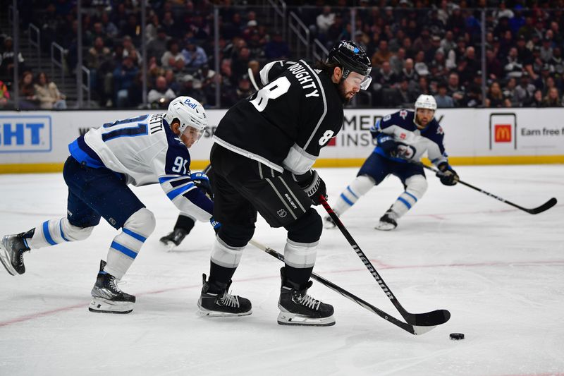 Dec 13, 2023; Los Angeles, California, USA; Los Angeles Kings defenseman Drew Doughty (8) moves the puck against Winnipeg Jets center Cole Perfetti (91) during the third period at Crypto.com Arena. Mandatory Credit: Gary A. Vasquez-USA TODAY Sports