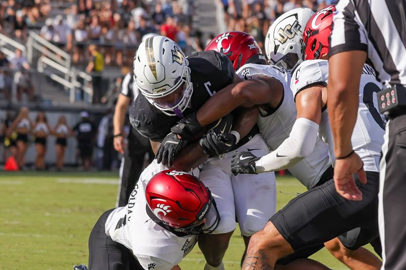 Oct 12, 2024; Orlando, Florida, USA; UCF Knights running back RJ Harvey (7) is tackled during the second quarter against the Cincinnati Bearcats at FBC Mortgage Stadium. Mandatory Credit: Mike Watters-Imagn Images