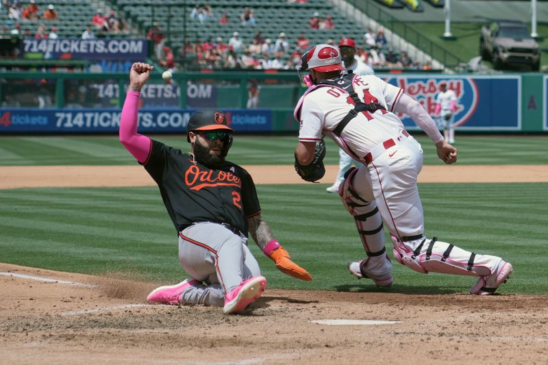 May 11, 2025; Anaheim, California, USA; Baltimore Orioles third baseman Emmanuel Rivera (26) slides into home plate to beat a throw to Los Angeles Angels catcher Logan O'Hoppe (14) to score in the fifth inning at Angel Stadium. Mandatory Credit: Kirby Lee-Imagn Images