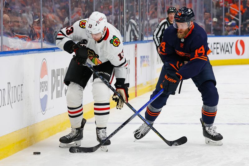 Jan 25, 2024; Edmonton, Alberta, CAN; Chicago Blackhawks forward Zach Sanford (13) and Edmonton Oilers defensemen Mattias Ekholm (14) battle along the boards for a loose puck during the second period at Rogers Place. Mandatory Credit: Perry Nelson-USA TODAY Sports