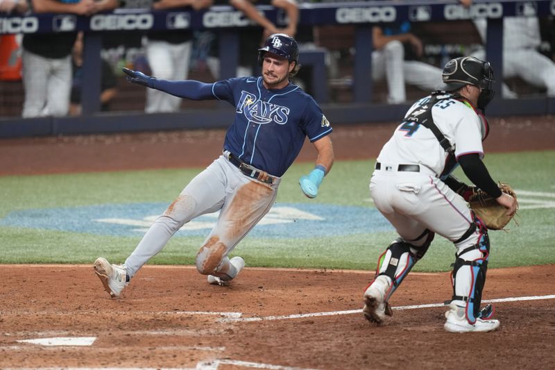 Aug 30, 2023; Miami, Florida, USA; Tampa Bay Rays right fielder Josh Lowe (15) slides safely into home plate as Miami Marlins catcher Nick Fortes (4) looks on in the tenth inning at loanDepot Park. Mandatory Credit: Jim Rassol-USA TODAY Sports