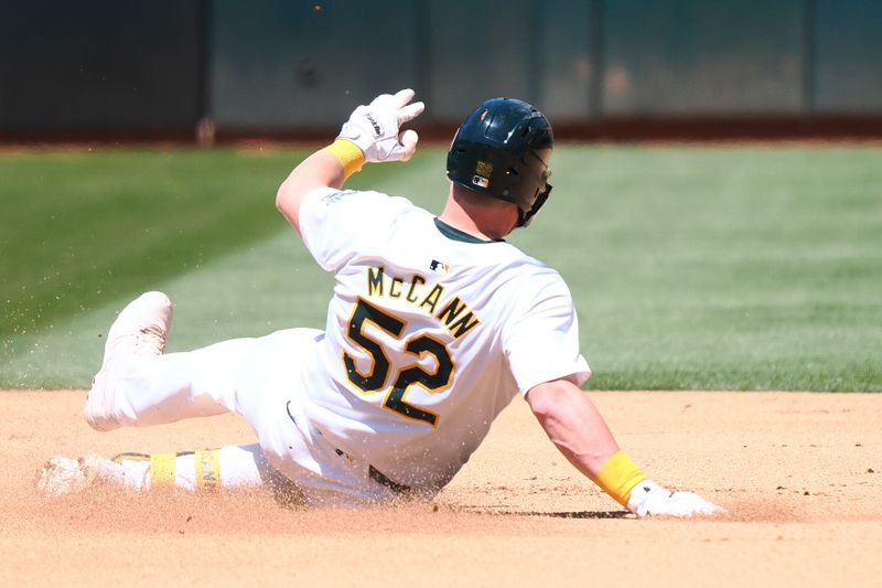 May 23, 2024; Oakland, California, USA; Oakland Athletics catcher Kyle McCann (52) slides safely into second base for a double against the Colorado Rockies during the seventh inning at Oakland-Alameda County Coliseum. Mandatory Credit: Kelley L Cox-USA TODAY Sports