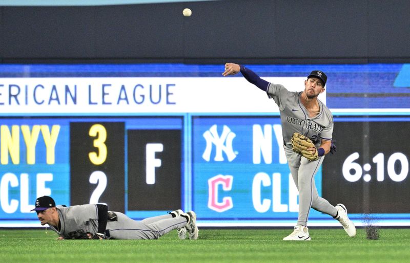 Apr 13, 2024; Toronto, Ontario, CAN;  Colorado Rockies left fielder Nolan Jones (22) throws the ball after catching a fly ball hit by Toronto Blue Jays second baseman Cavan Biggio (not shown) as center fielder Brenton Doyle (9) looks on in the first inning at Rogers Centre. Mandatory Credit: Dan Hamilton-USA TODAY Sports
