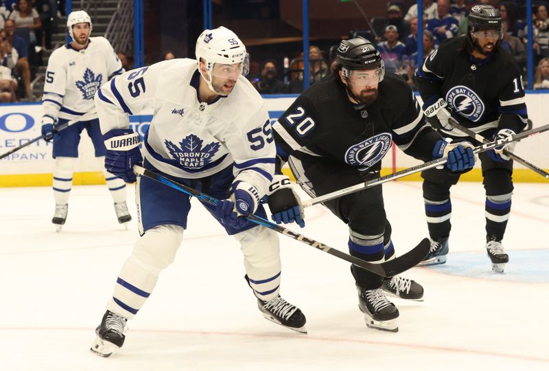 Apr 17, 2024; Tampa, Florida, USA; Toronto Maple Leafs defenseman Mark Giordano (55) and Tampa Bay Lightning left wing Nicholas Paul (20) skate for a loose puck during the third period at Amalie Arena. Mandatory Credit: Kim Klement Neitzel-USA TODAY Sports