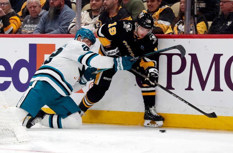 Mar 14, 2024; Pittsburgh, Pennsylvania, USA; Pittsburgh Penguins right wing Reilly Smith (19) moves the puck against San Jose Sharks center Ryan Carpenter (left) during the third period at PPG Paints Arena. Pittsburgh won 6-3. Mandatory Credit: Charles LeClaire-USA TODAY Sports