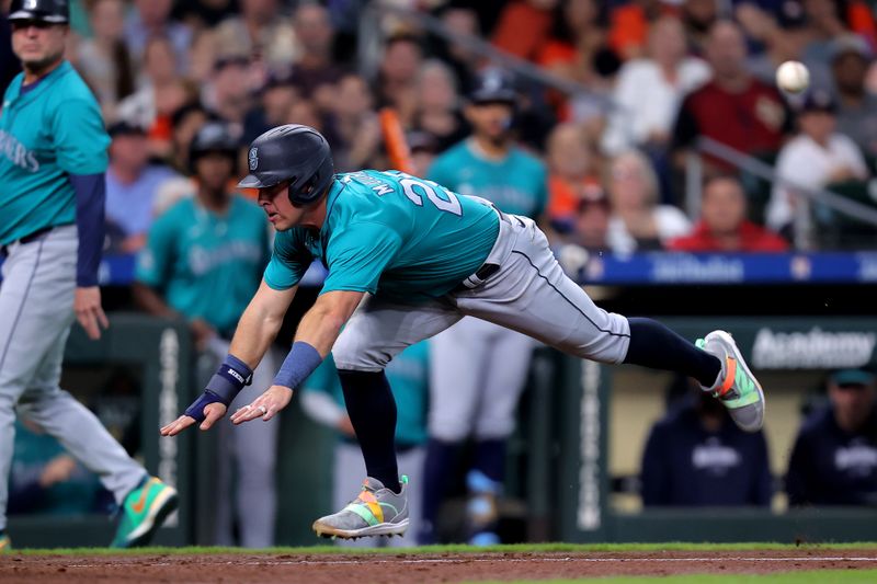 May 5, 2024; Houston, Texas, USA; Seattle Mariners shortstop Dylan Moore (25) slides into home plate to score a run against the Houston Astros during the eighth inning at Minute Maid Park. Mandatory Credit: Erik Williams-USA TODAY Sports