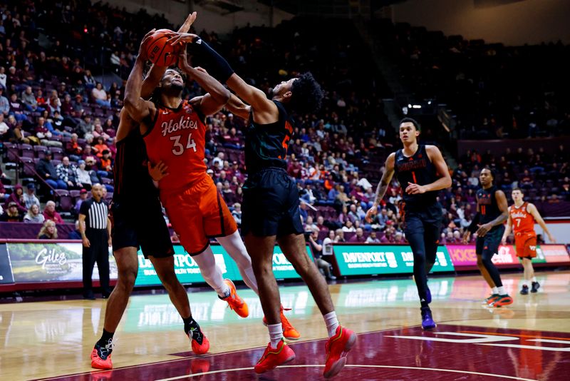 Jan 4, 2025; Blacksburg, Virginia, USA; Virginia Tech Hokies forward Mylyjael Poteat (34) shoots the ball against Miami Hurricanes guard Jalen Blackmon (5) during the first half at Cassell Coliseum. Mandatory Credit: Peter Casey-Imagn Images