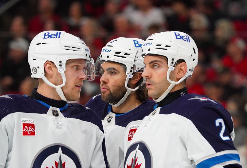 Mar 2, 2024; Raleigh, North Carolina, USA; Winnipeg Jets left wing Nikolaj Ehlers (27), left wing Alex Iafallo (9) and defenseman Dylan DeMelo (2) talk against the Carolina Hurricanes during the first period at PNC Arena. Mandatory Credit: James Guillory-USA TODAY Sports