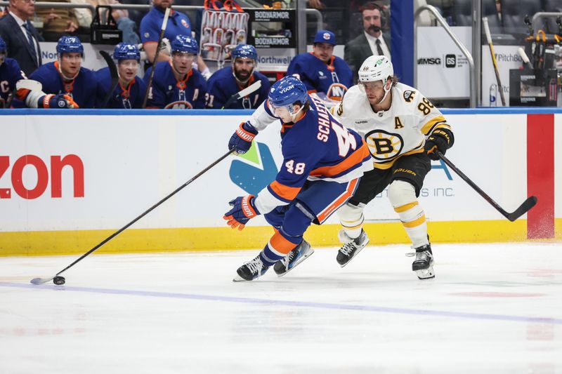 Nov 26, 2025; Elmont, New York, USA; New York Islanders defenseman Matthew Schaefer (48) and Boston Bruins right wing David Pastrnak (88) battle for control of the puck in the third period at UBS Arena. Mandatory Credit: Wendell Cruz-Imagn Images