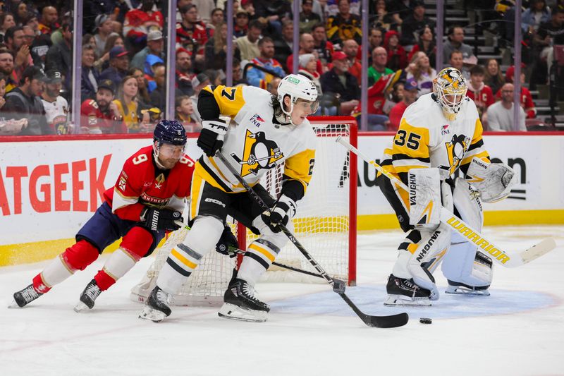 Dec 8, 2023; Sunrise, Florida, USA; Pittsburgh Penguins defenseman Ryan Graves (27) moves the puck ahead of Florida Panthers center Sam Bennett (9) during the second period at Amerant Bank Arena. Mandatory Credit: Sam Navarro-USA TODAY Sports