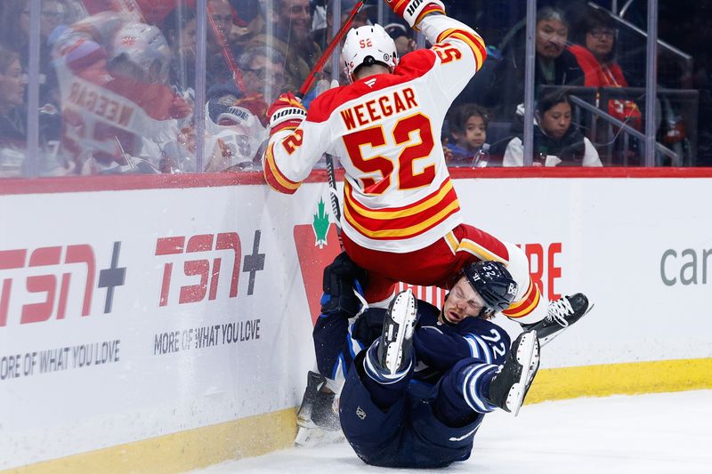 Jan 26, 2025; Winnipeg, Manitoba, CAN; Calgary Flames defenseman MacKenzie Weegar (52) collides with Winnipeg Jets forward Mason Appleton (22) during the second period at Canada Life Centre. Mandatory Credit: Terrence Lee-Imagn Images
