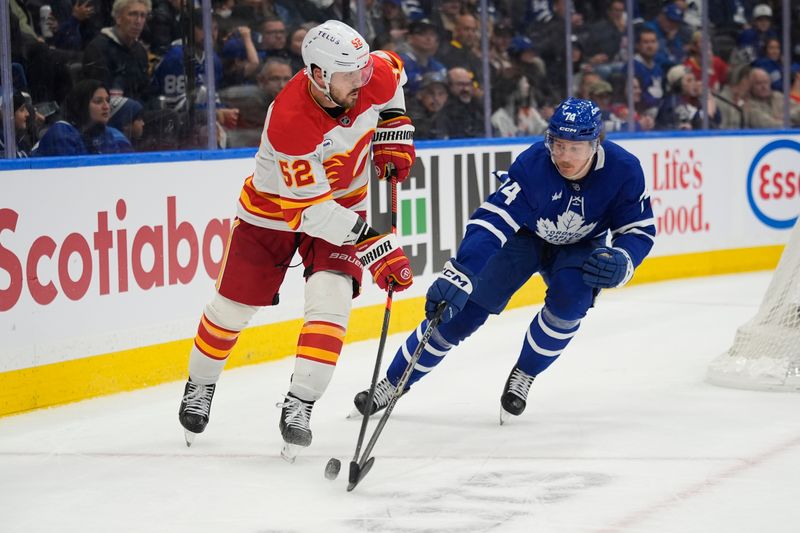 Oct 28, 2025; Toronto, Ontario, CAN; Toronto Maple Leafs forward Bobby McMann (74) knocks the puck off the stick of Calgary Flames defenseman MacKenzie Weegar (52) during the third period at Scotiabank Arena. Mandatory Credit: John E. Sokolowski-Imagn Images