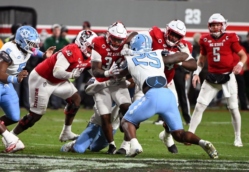 Nov 25, 2023; Raleigh, North Carolina, USA; North Carolina State Wolfpack running back Delbert Mimms III (34) runs the ball against the North Carolina Tar Heels during the first half at Carter-Finley Stadium. Mandatory Credit: Rob Kinnan-USA TODAY Sports