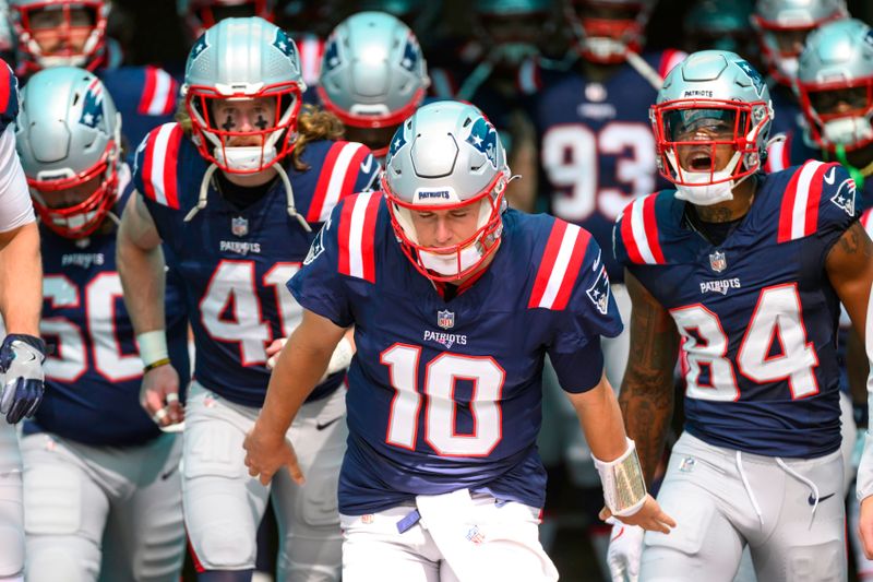 New England Patriots quarterback Mac Jones (10) leads defensive back Brenden Schooler (41), wide receiver Kendrick Bourne (84) and the rest of the team onto the field before the start of an NFL football game against the Miami Dolphins, Sunday, Oct. 29, 2023, in Miami Gardens, Fla. (AP Photo/Doug Murray)