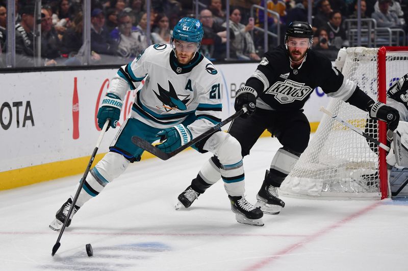 Jan 7, 2026; Los Angeles, California, USA; San Jose Sharks center Alexander Wennberg (21) moves the puck against Los Angeles Kings defenseman Joel Edmundson (6) during the first period at Crypto.com Arena. Mandatory Credit: Gary A. Vasquez-Imagn Images
